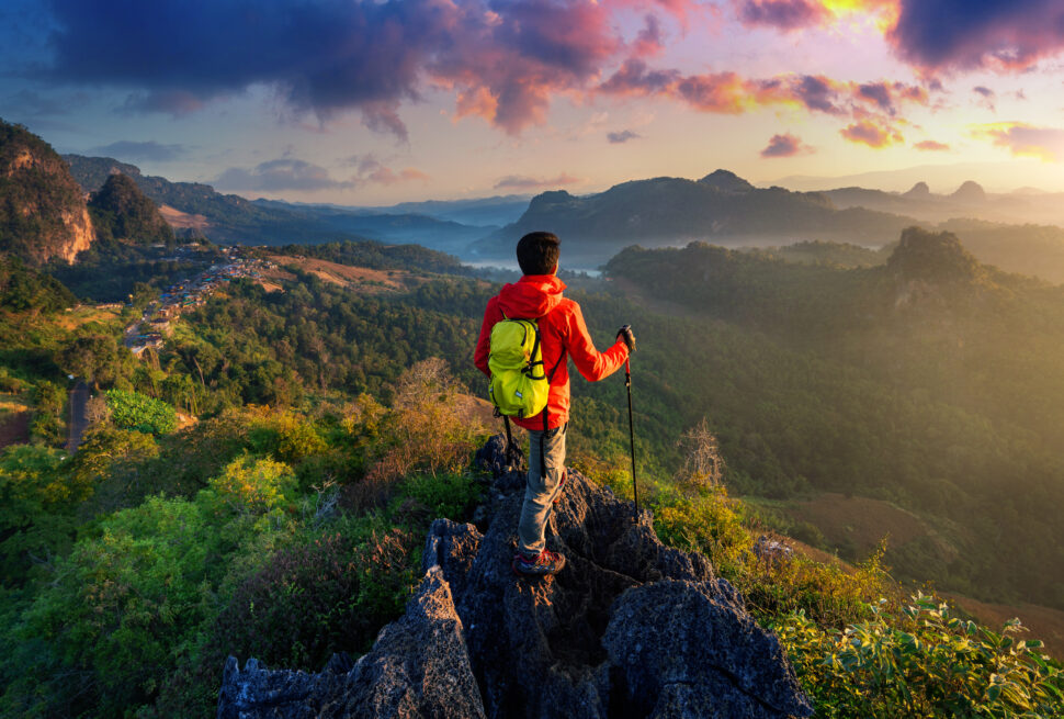 Backpacker watching sunrise over valleys and hills in Himachal.
